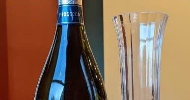 Wine bottle and glasses on table inside cozy cat cafe bar area