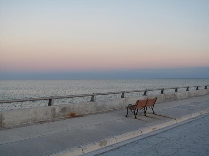 Empty seaside promenade bench at sunset along oceanfront