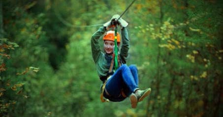 Thrill-seeker ziplining between trees on Sky Valley canopy course