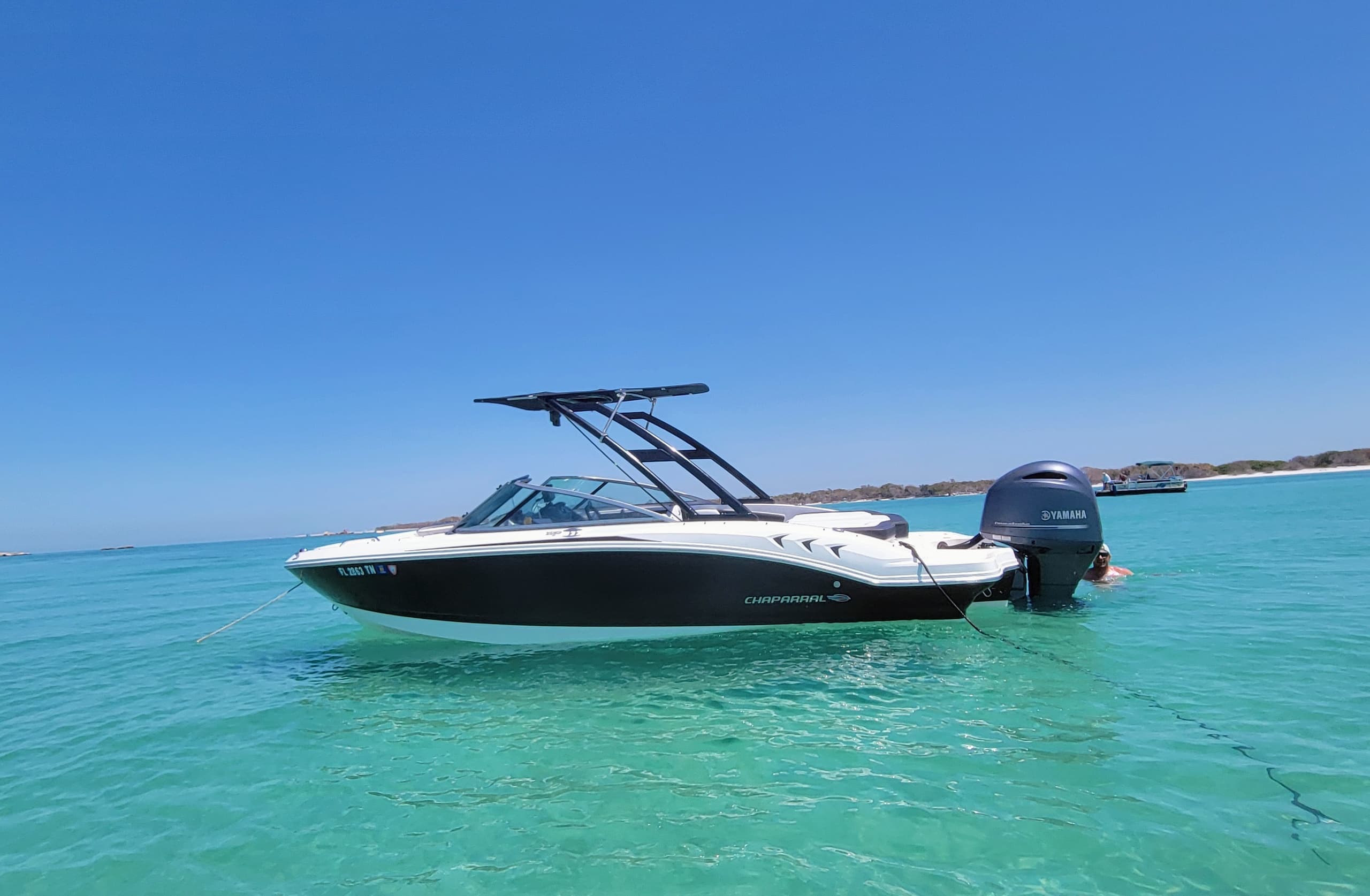 Wakeboat on turquoise flats under clear blue sky, tropical cruise