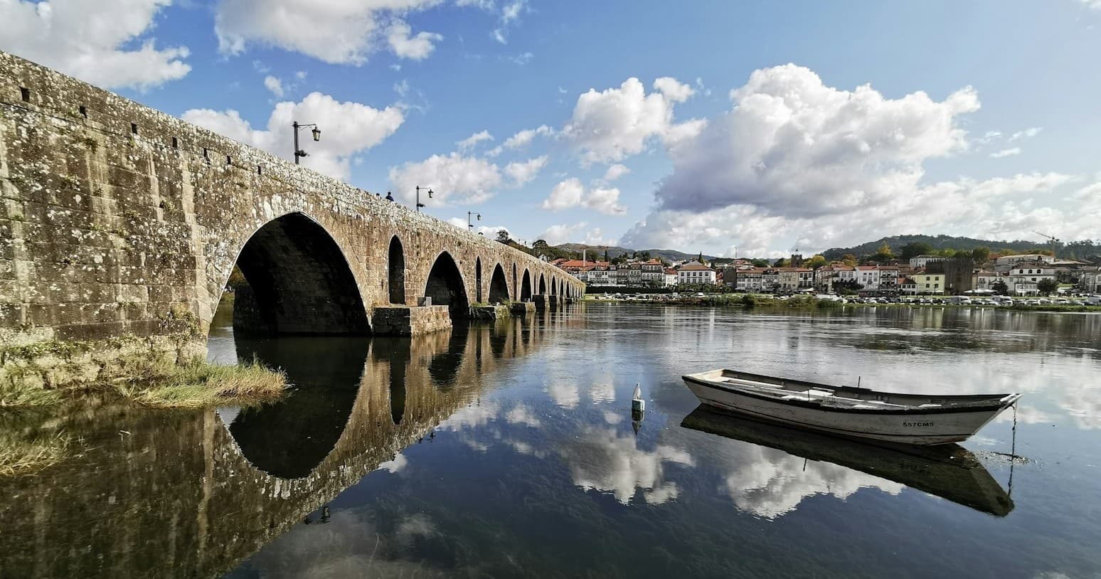 Historic stone bridge over reflective river in Portugal town