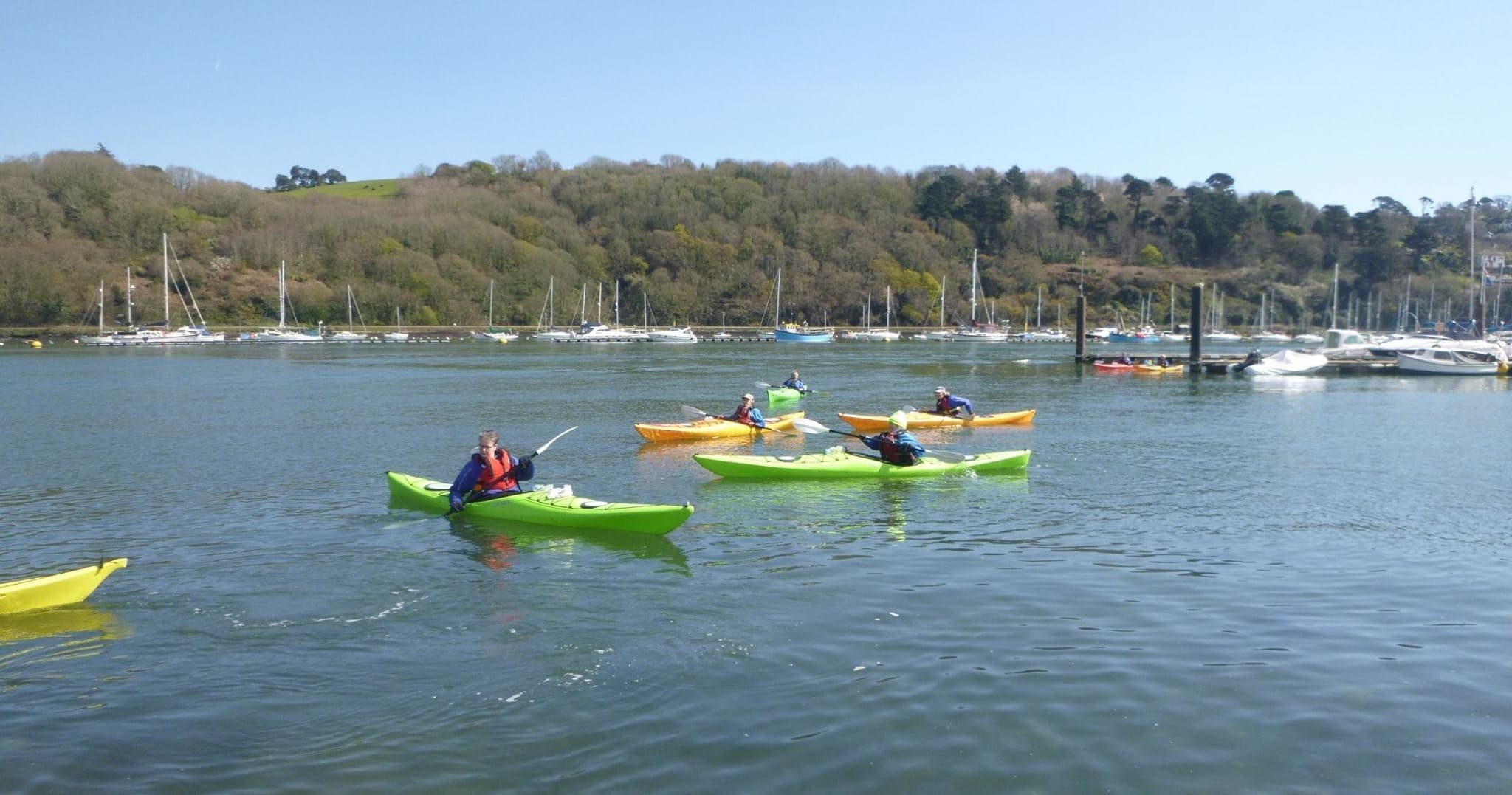 Multiple kayaks in calm bay with distant rocky islands