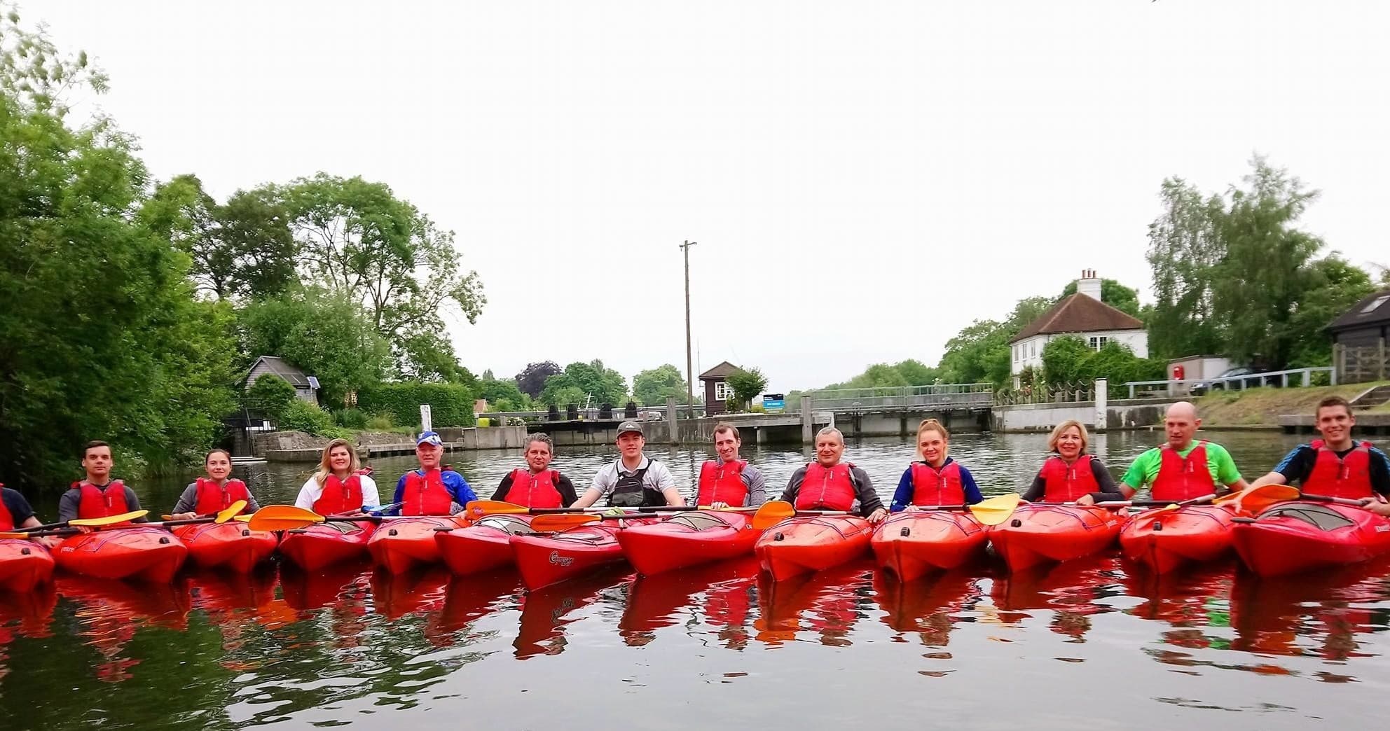 Group kayaking trip on the Thames in red sit-on-top kayaks