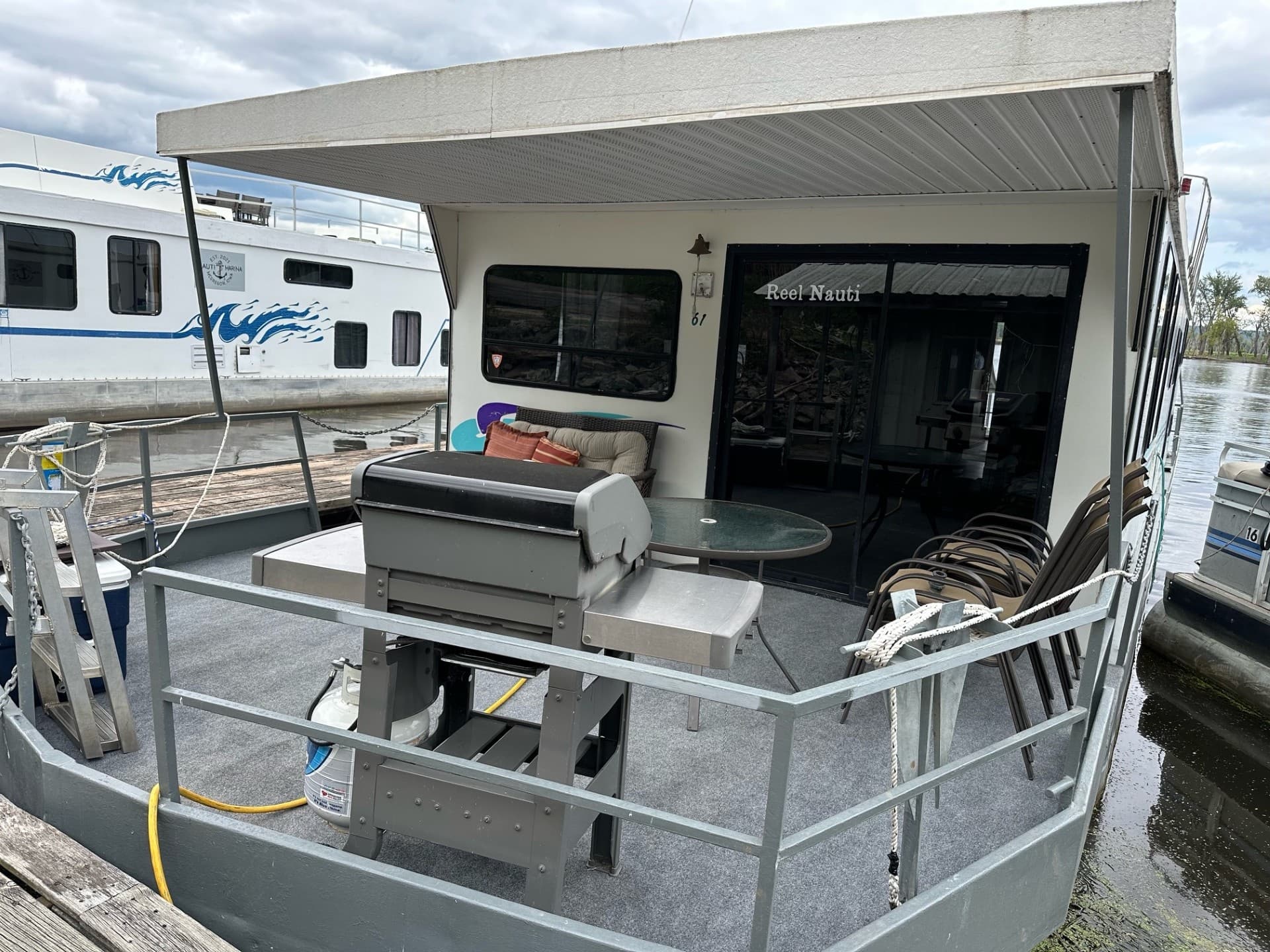 Houseboat stern and deck with grill docked at lakeside marina