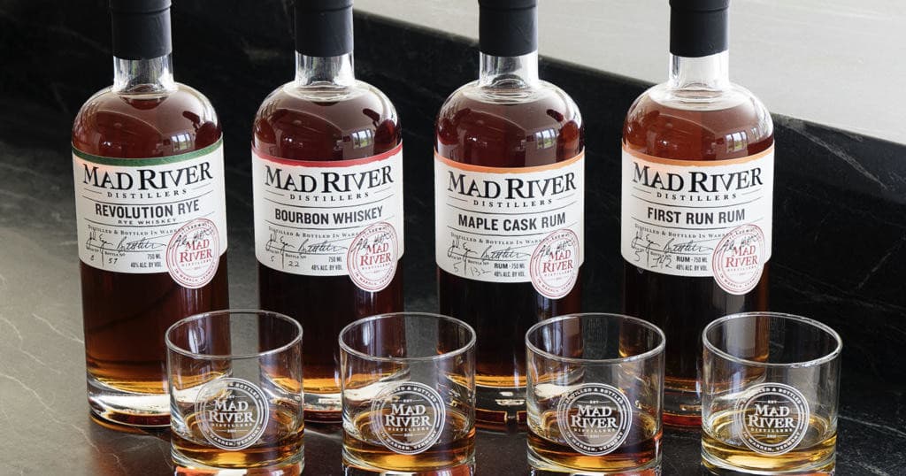 Bottles of Mad River whiskey lined on tasting bar indoors