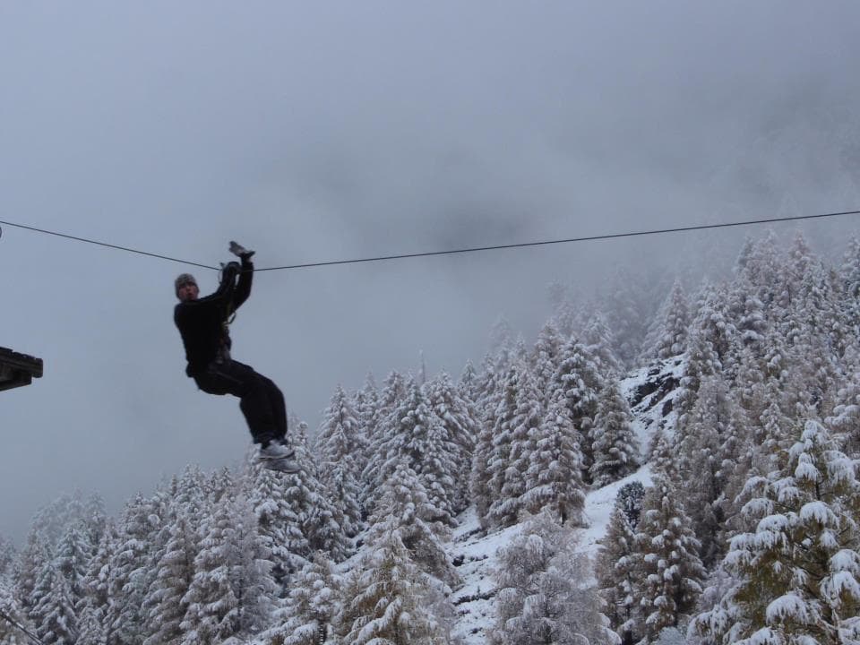 Winter zipline silhouette above snow-covered alpine forest