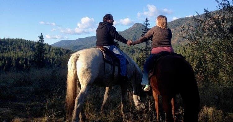 Two riders overlooking mountain valley at sunset on trail