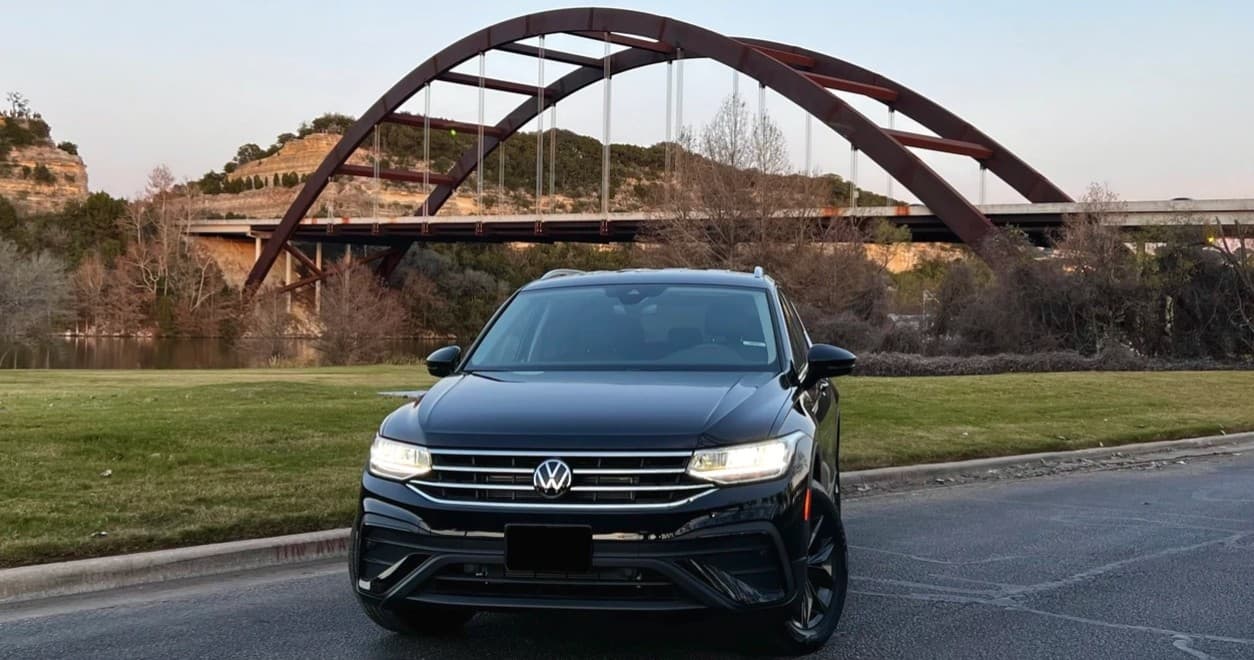 Black Volkswagen parked before Pennybacker Bridge at sunset