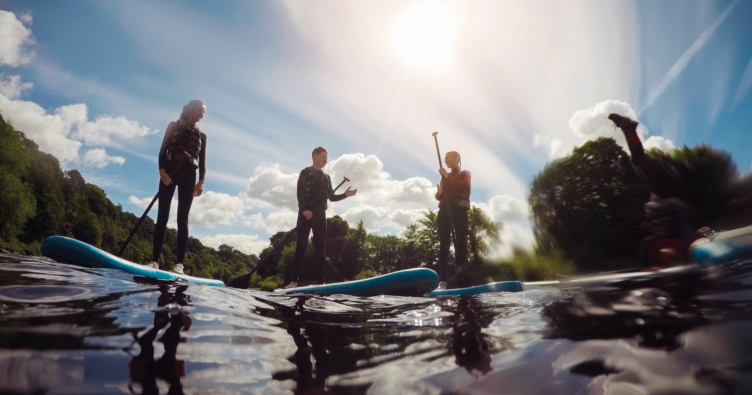 Silhouetted stand-up paddleboarders gliding on a reflective river