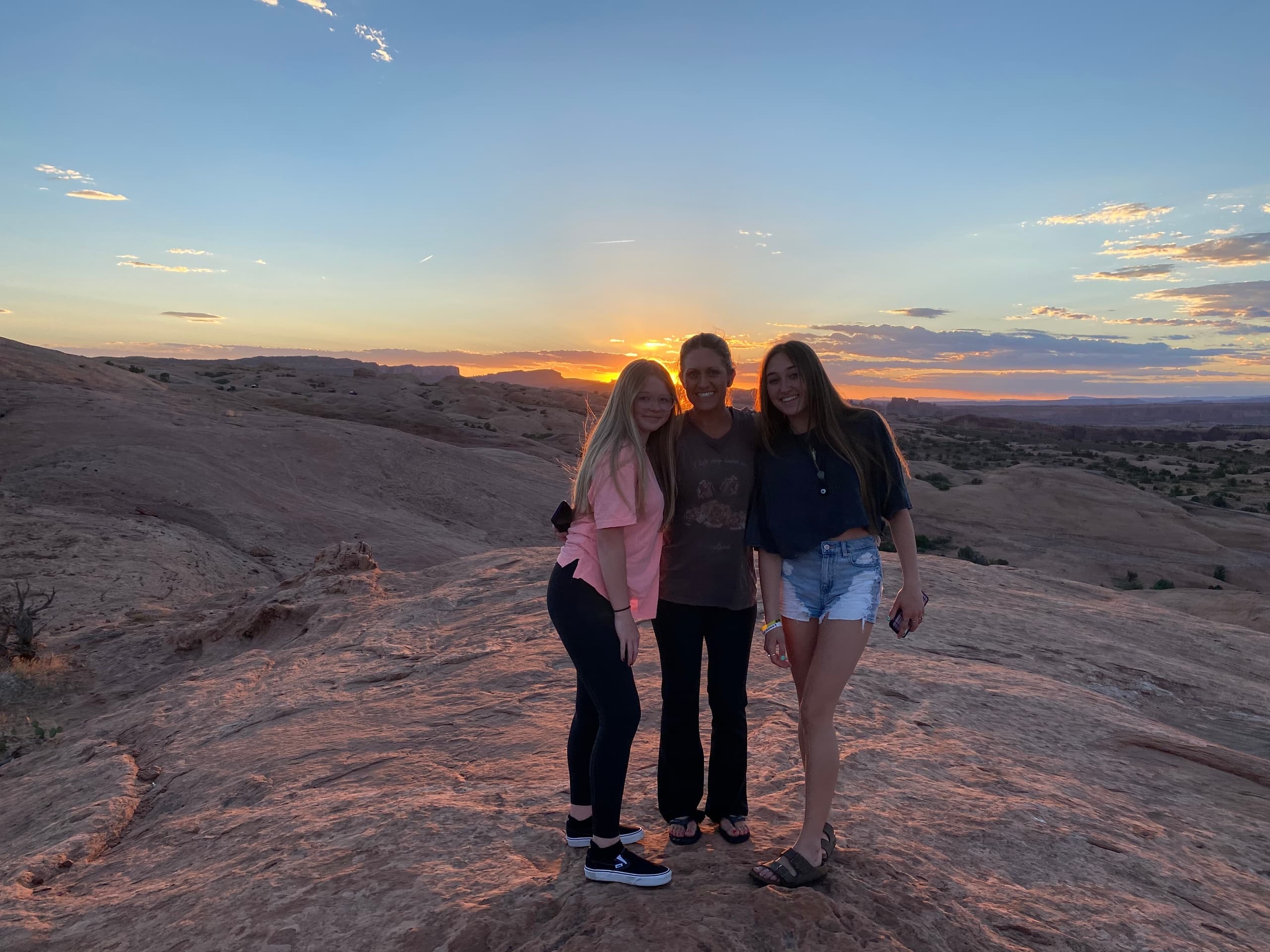 Friends posing at sunset on sandstone overlook during off-road tour
