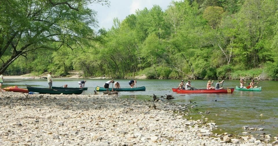 Multiple kayaks traversing wide scenic river with gravel banks