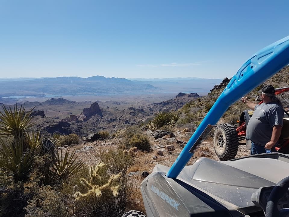 UTV parked on rocky ridge overlooking expansive desert and mountains