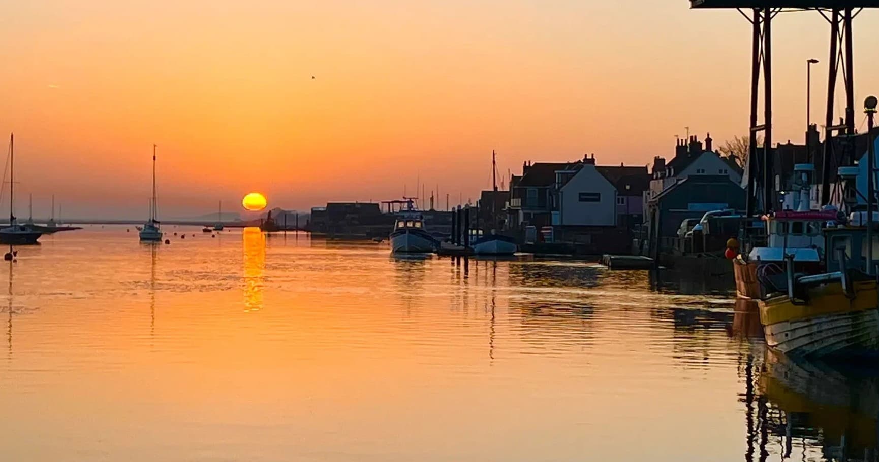 Harbor sunset with moored boats reflecting on calm marina