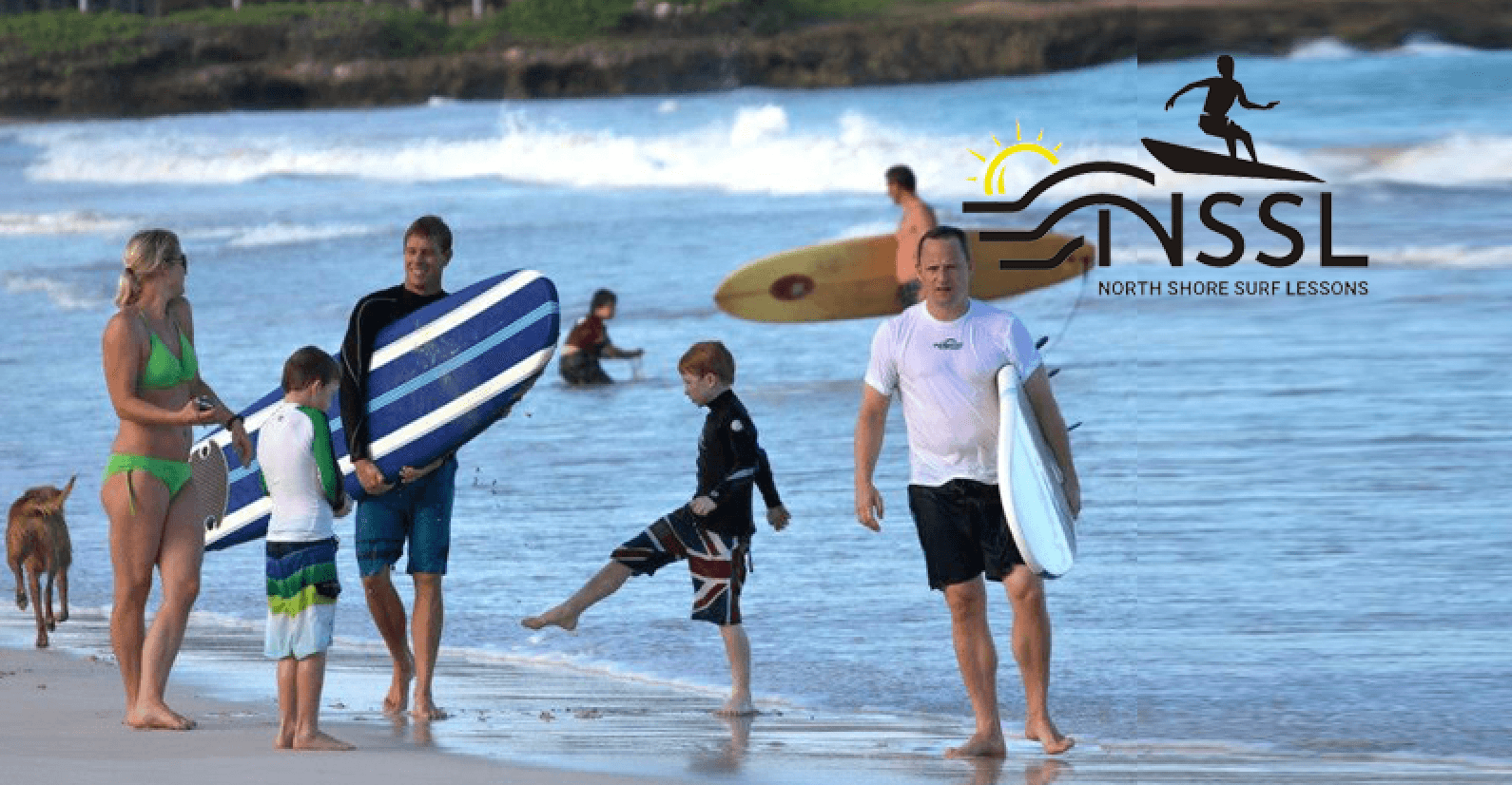 Group carrying surfboards on North Shore beach at sunrise