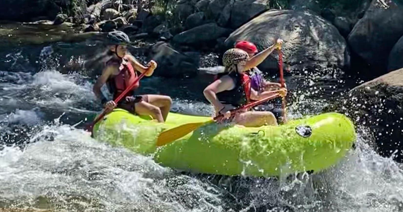 Two paddlers in lime raft running steep rocky whitewater rapids