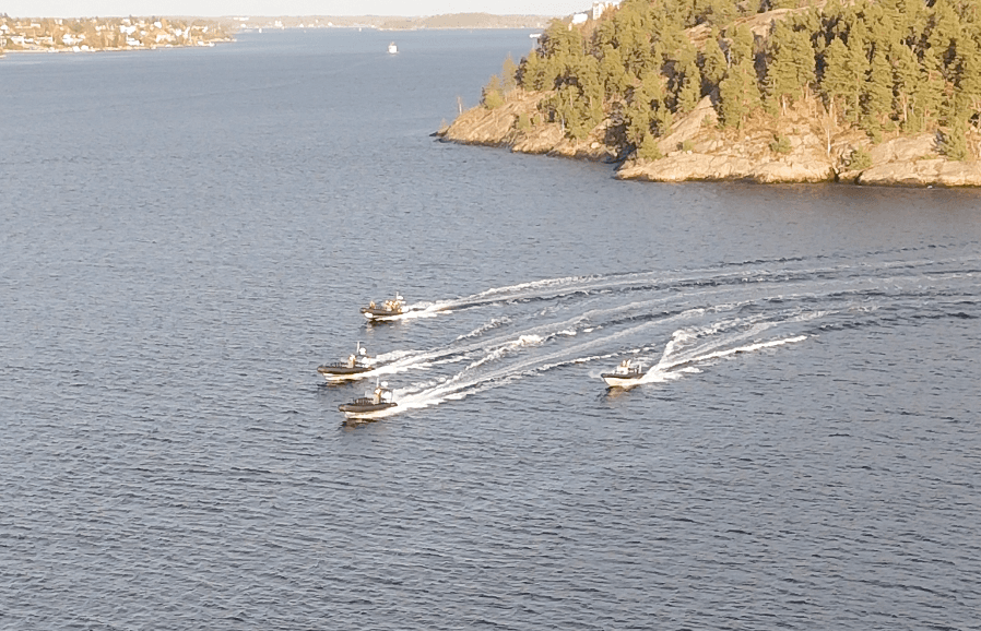 Three speedboats cutting through coastal waters near shoreline