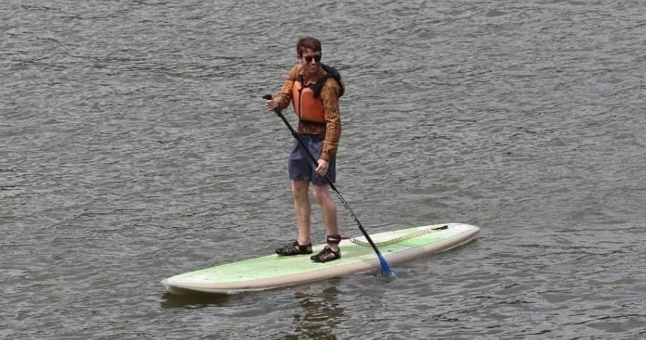 Standup paddleboarder balancing on open river water