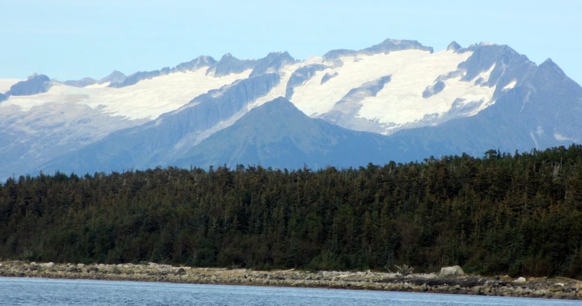 Glacier-capped mountains above coastal forest and ocean view