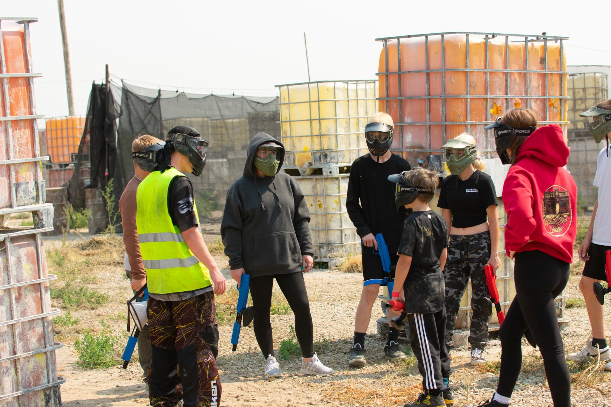 Mixed-age players receiving safety briefing at outdoor paintball field