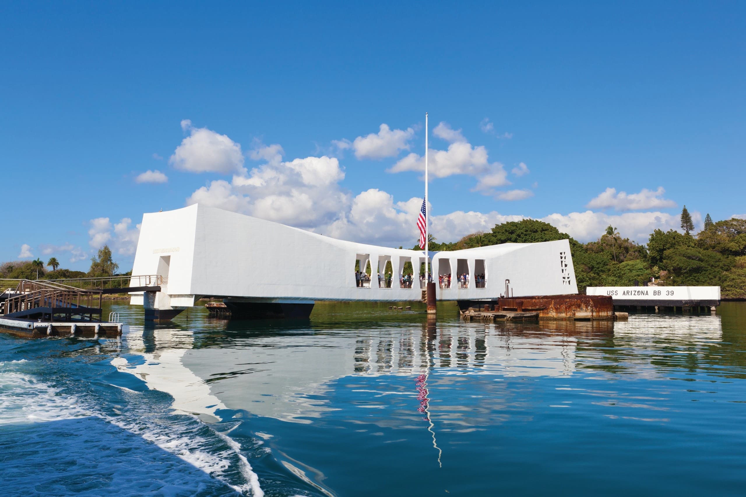 Sunlit harbor memorial building floating over blue water with mountains