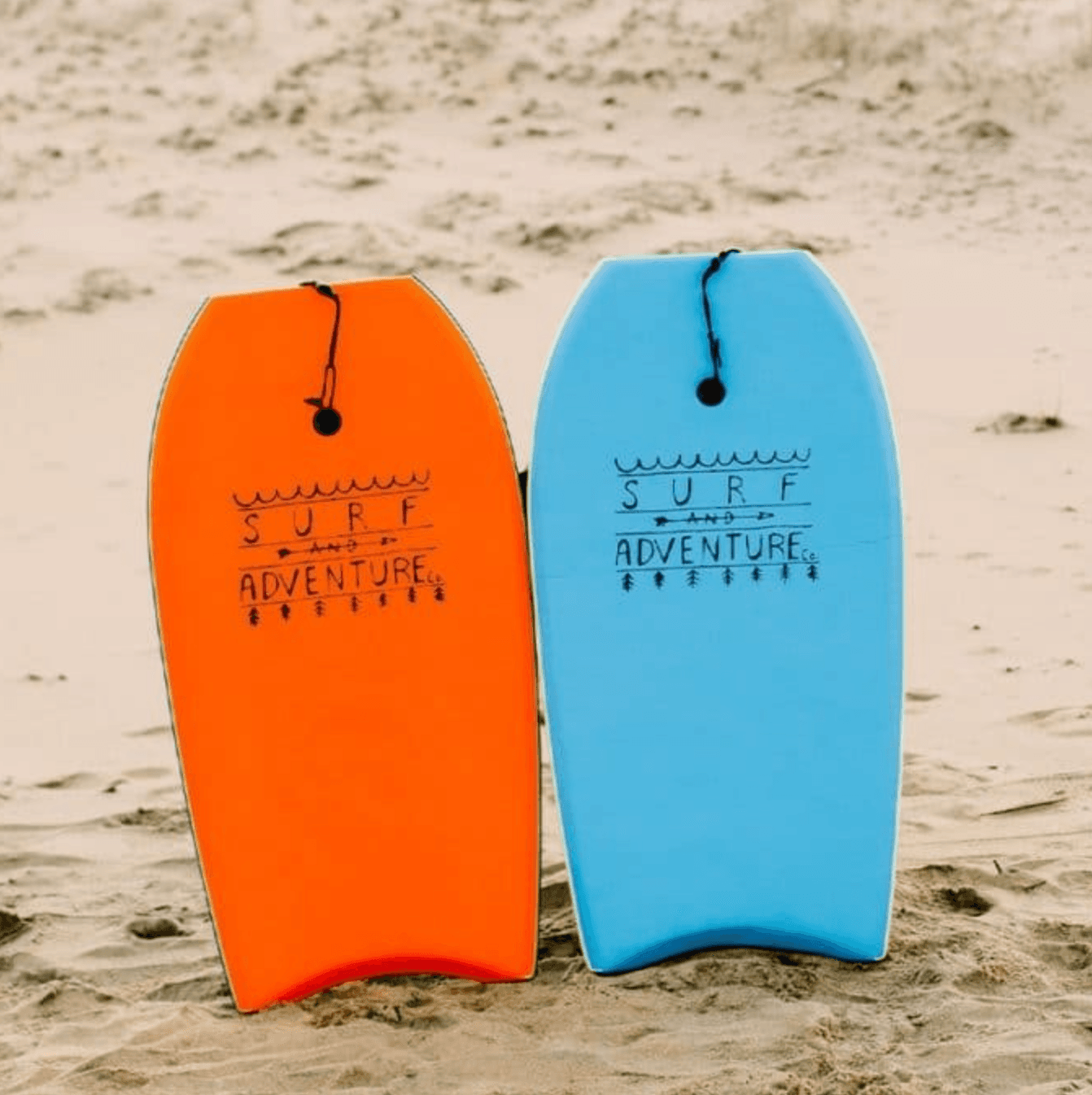 Pair of boogie/body boards propped on sandy beach for surfing fun