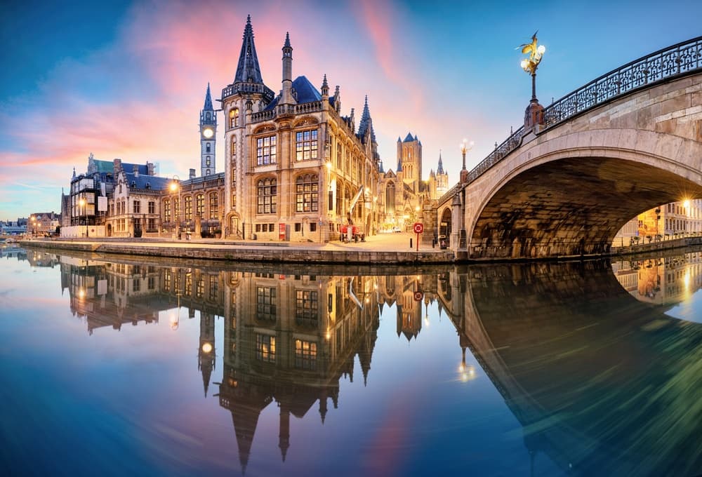 Bridge and Gothic buildings reflecting on Ghent canal at sunset
