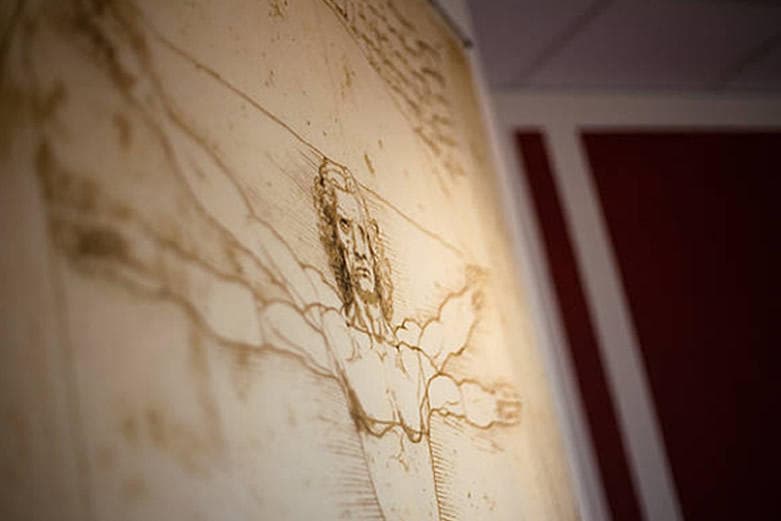 Close-up of Vitruvian sketch wall art inside themed escape room exhibit