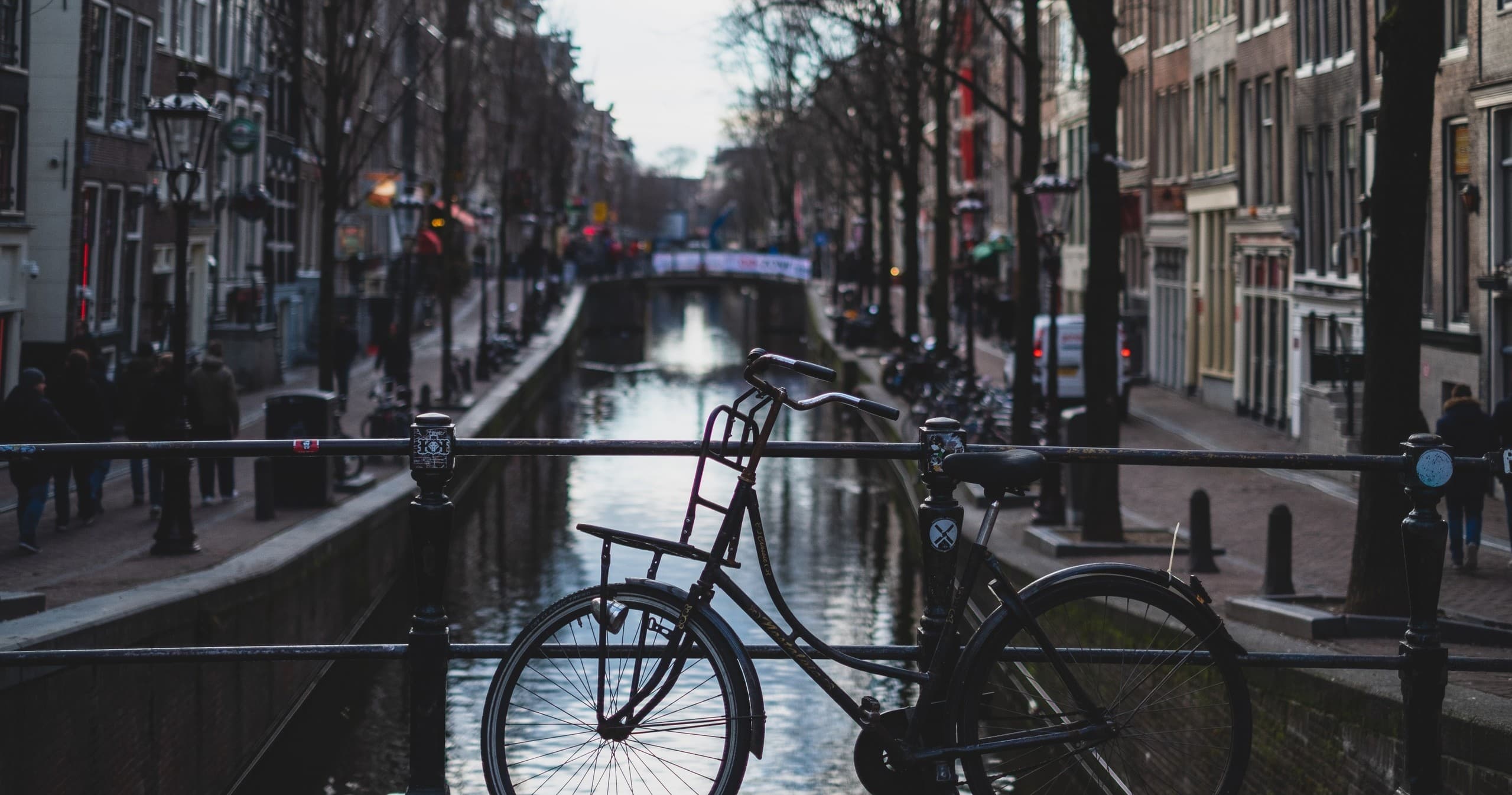 Bicycles parked on canal bridge in Amsterdam at dusk