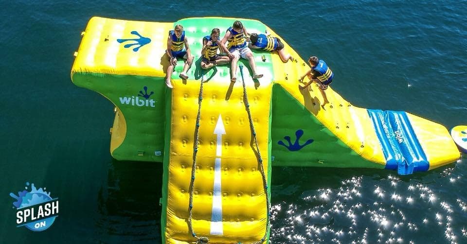 Large inflatable slide and platform on lake with people sliding