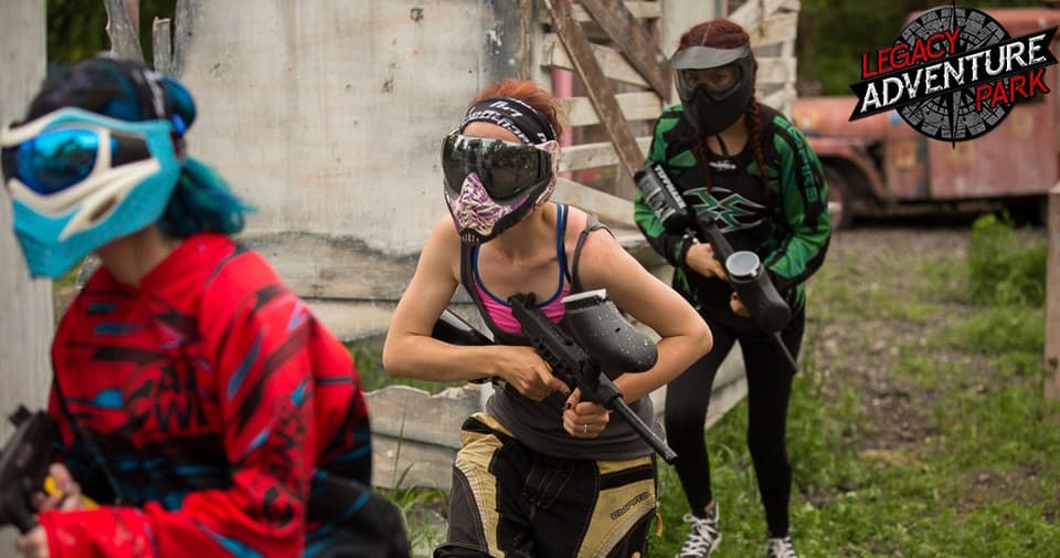 Team running through outdoor paintball field in tactical game session