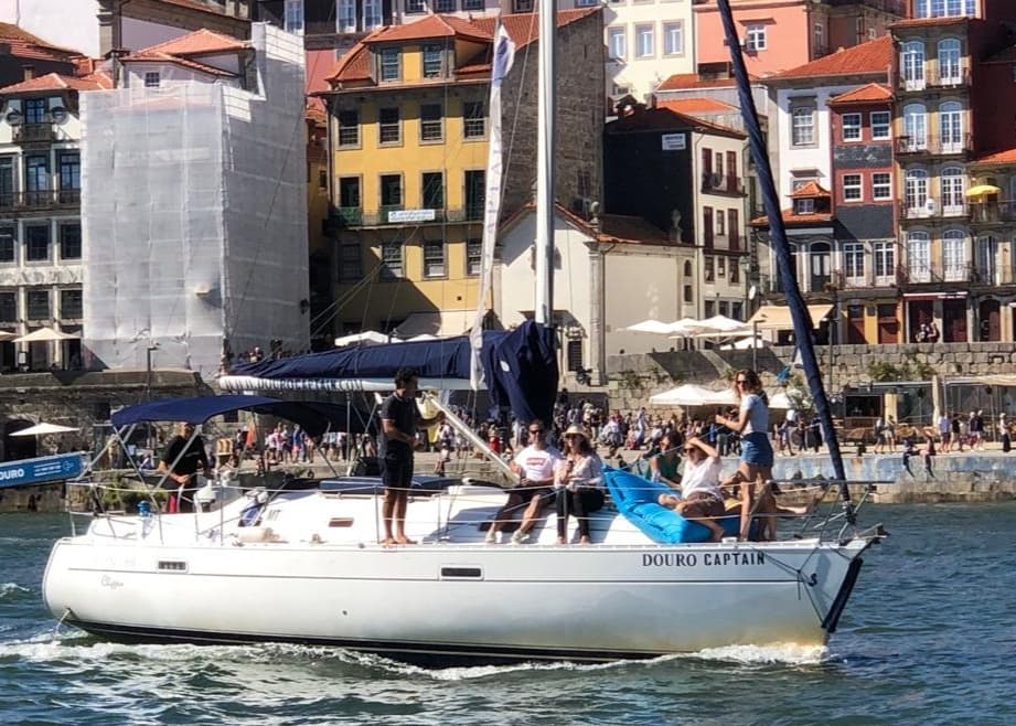 Group sailing on white yacht past historic waterfront in Porto