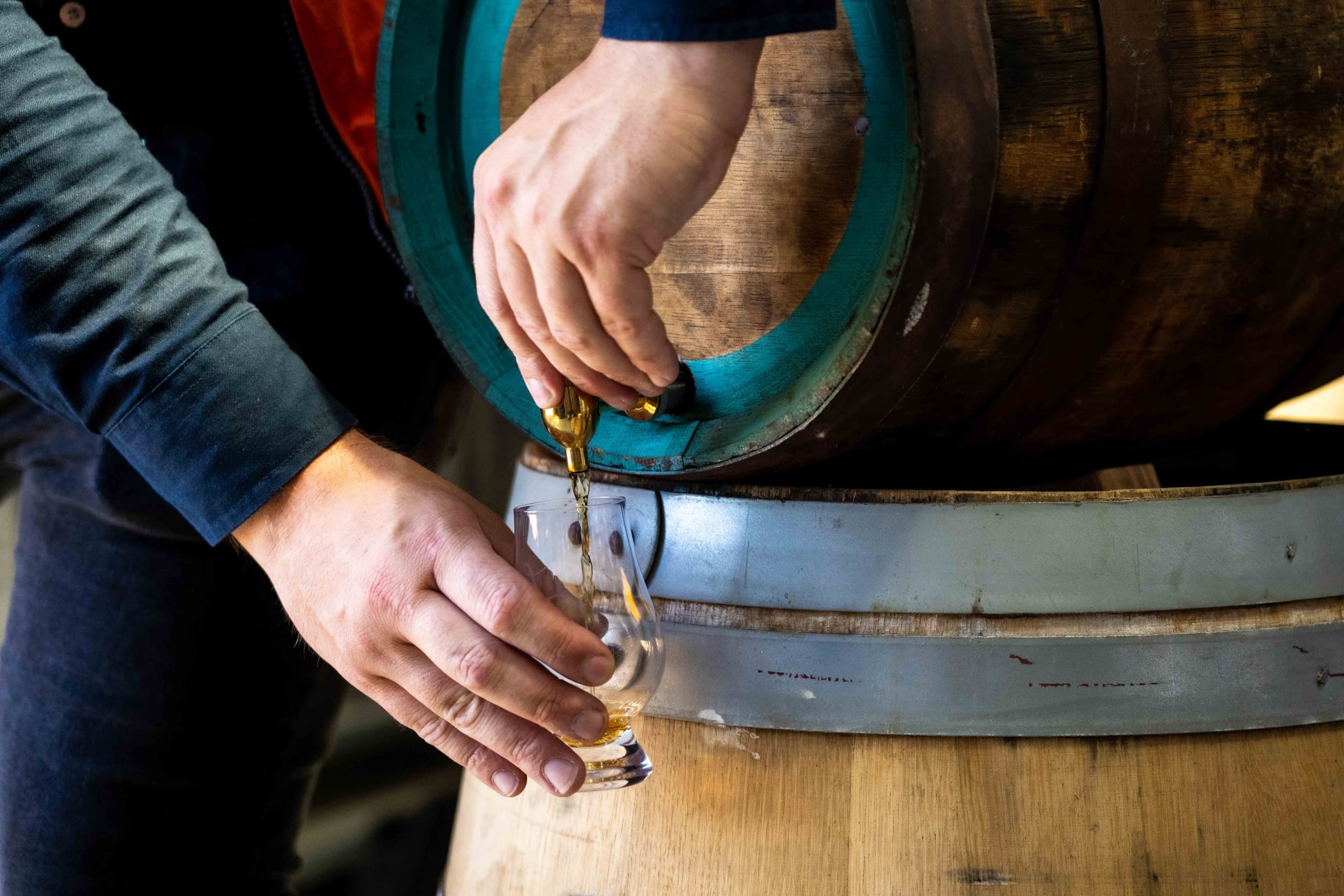 Pouring spirit sample from cask during distillery barrel tasting