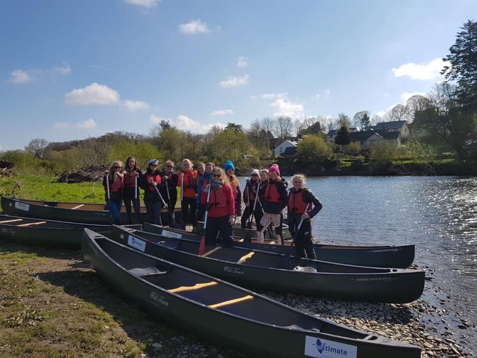 Group launching canoes on scenic riverside near village