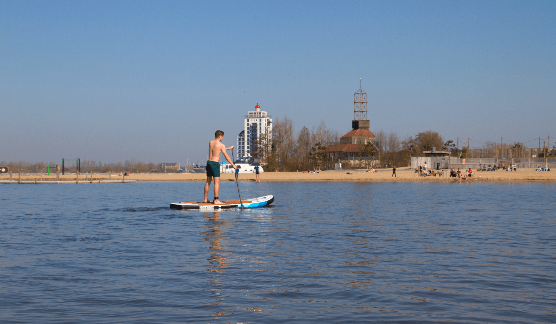 Paddleboarder cruising calm water with distant shoreline view