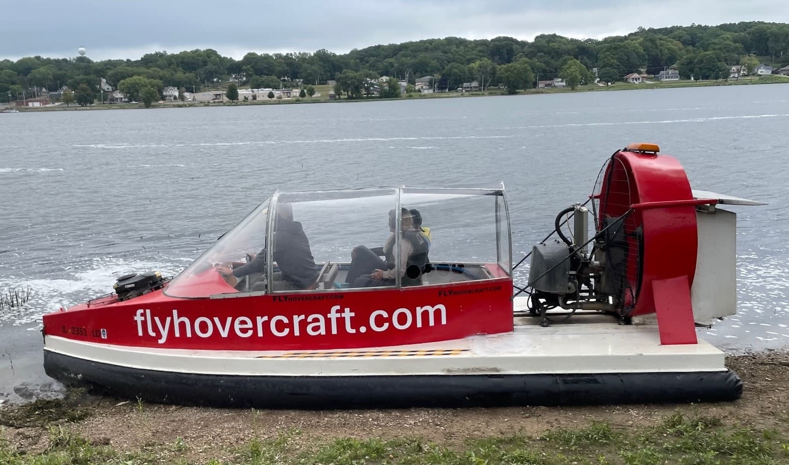 Red hovercraft cruising near lakeshore, scenic water tour