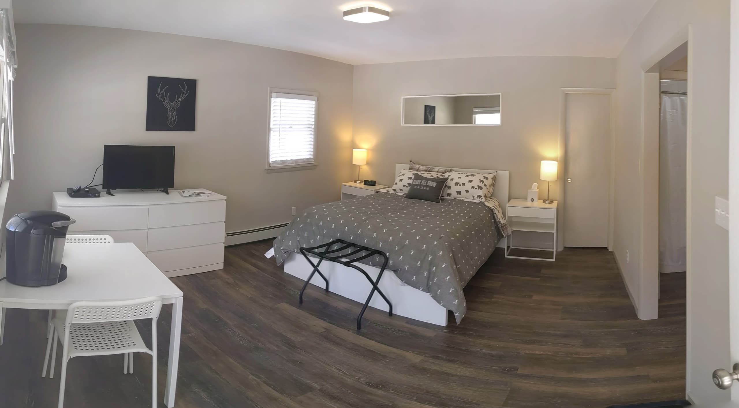 Panoramic studio bedroom view with dresser, desk, and bed