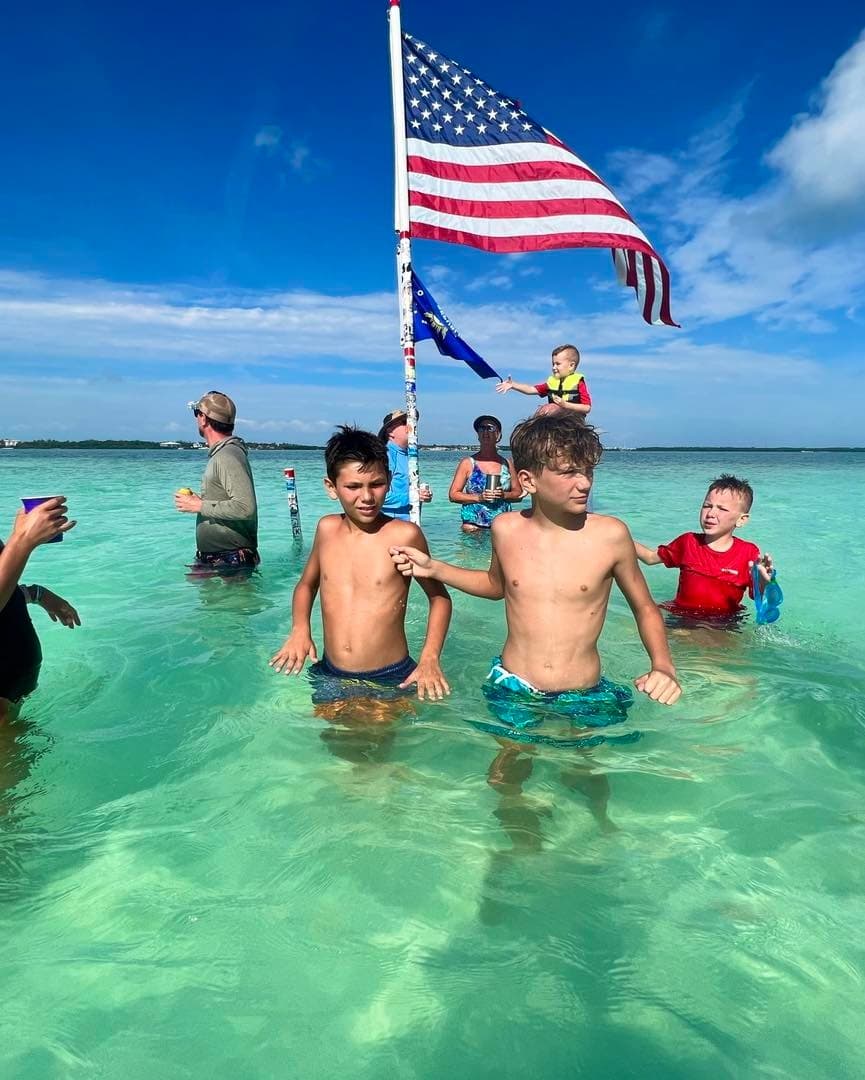 Children wading in clear tropical shallow water with flag
