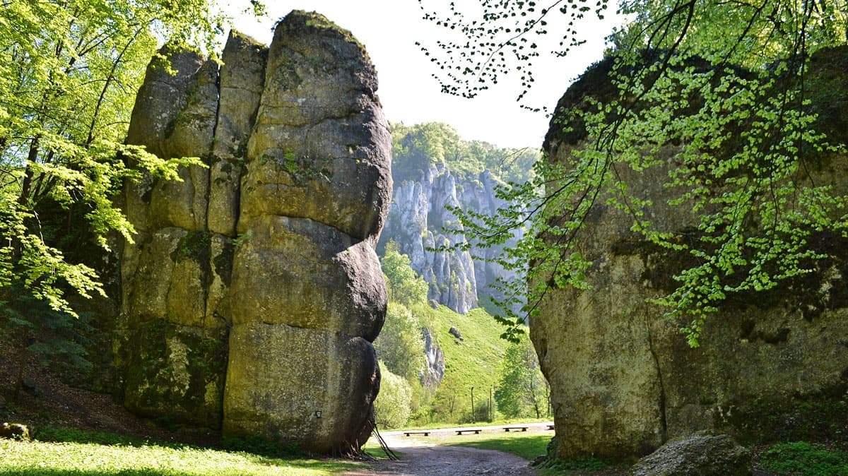 Hikers walking through limestone rock gate in Ojcow park