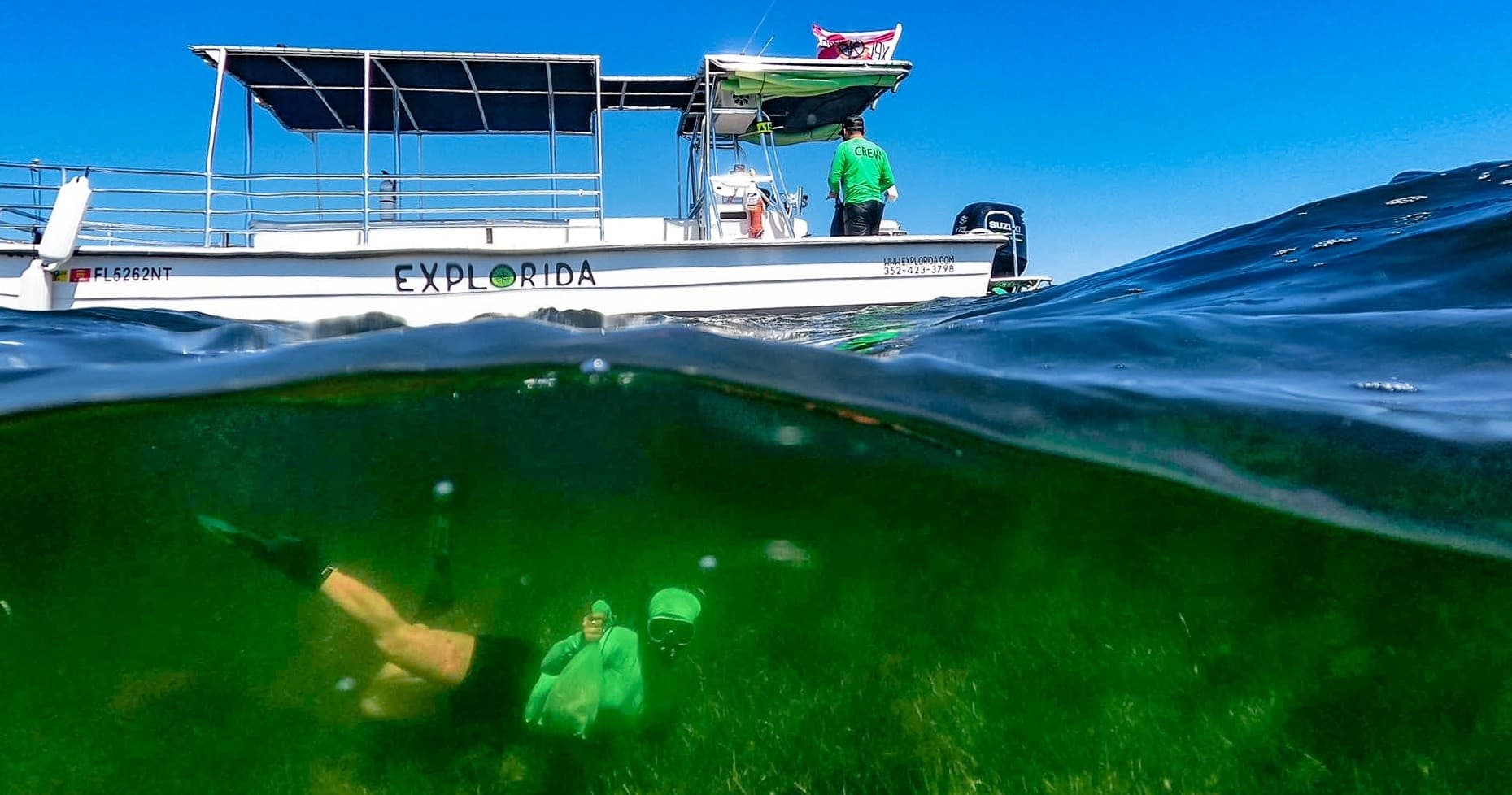 Over-under shot of boat and snorkeler in shallow coastal water