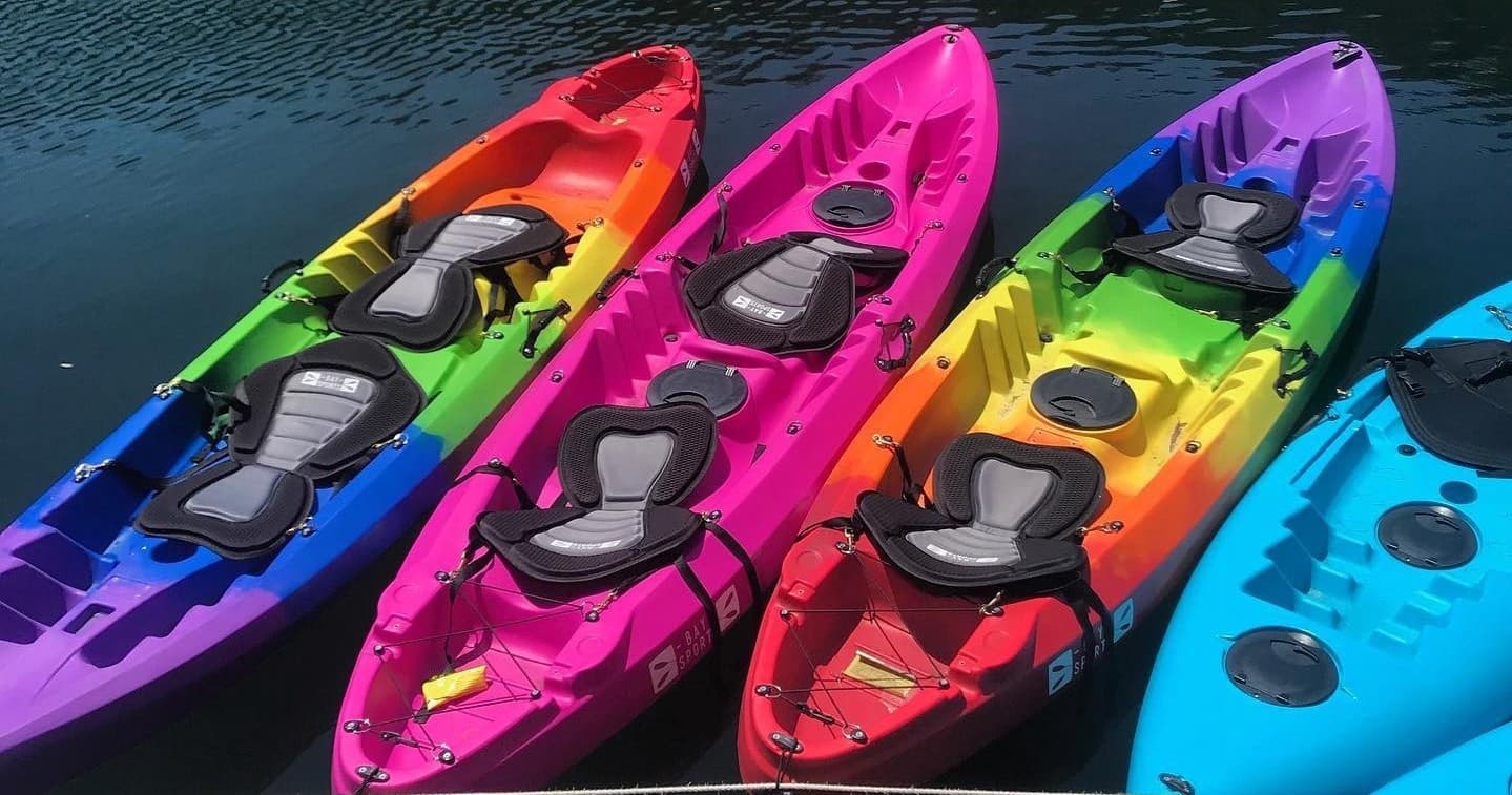 Colorful recreational kayaks lined up on calm water at dock