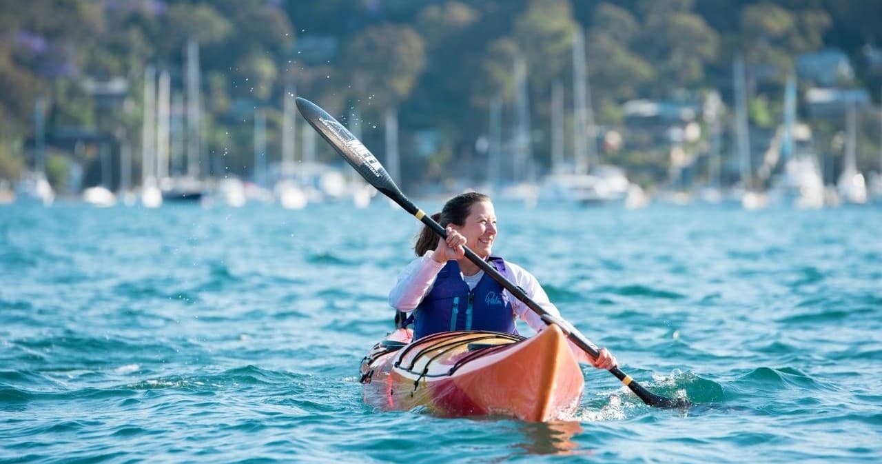 Solo kayaker paddling near marina on turquoise open water