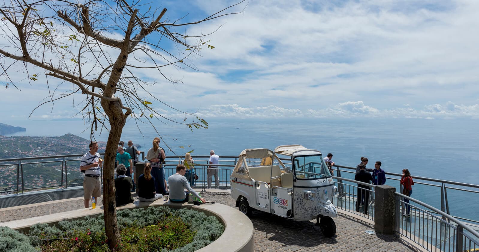 Scenic viewpoint with tuk-tuk and tourists overlooking Madeira sea