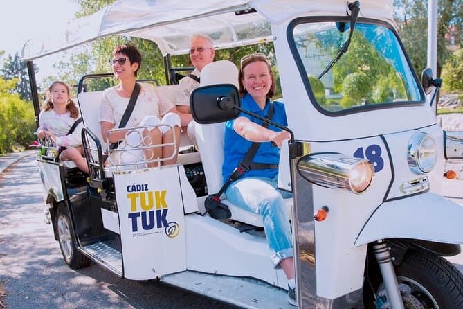 Family riding Cadiz tuk-tuk through sunny coastal streets