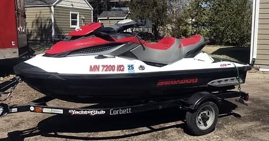 Red and black jet ski on trailer in residential driveway