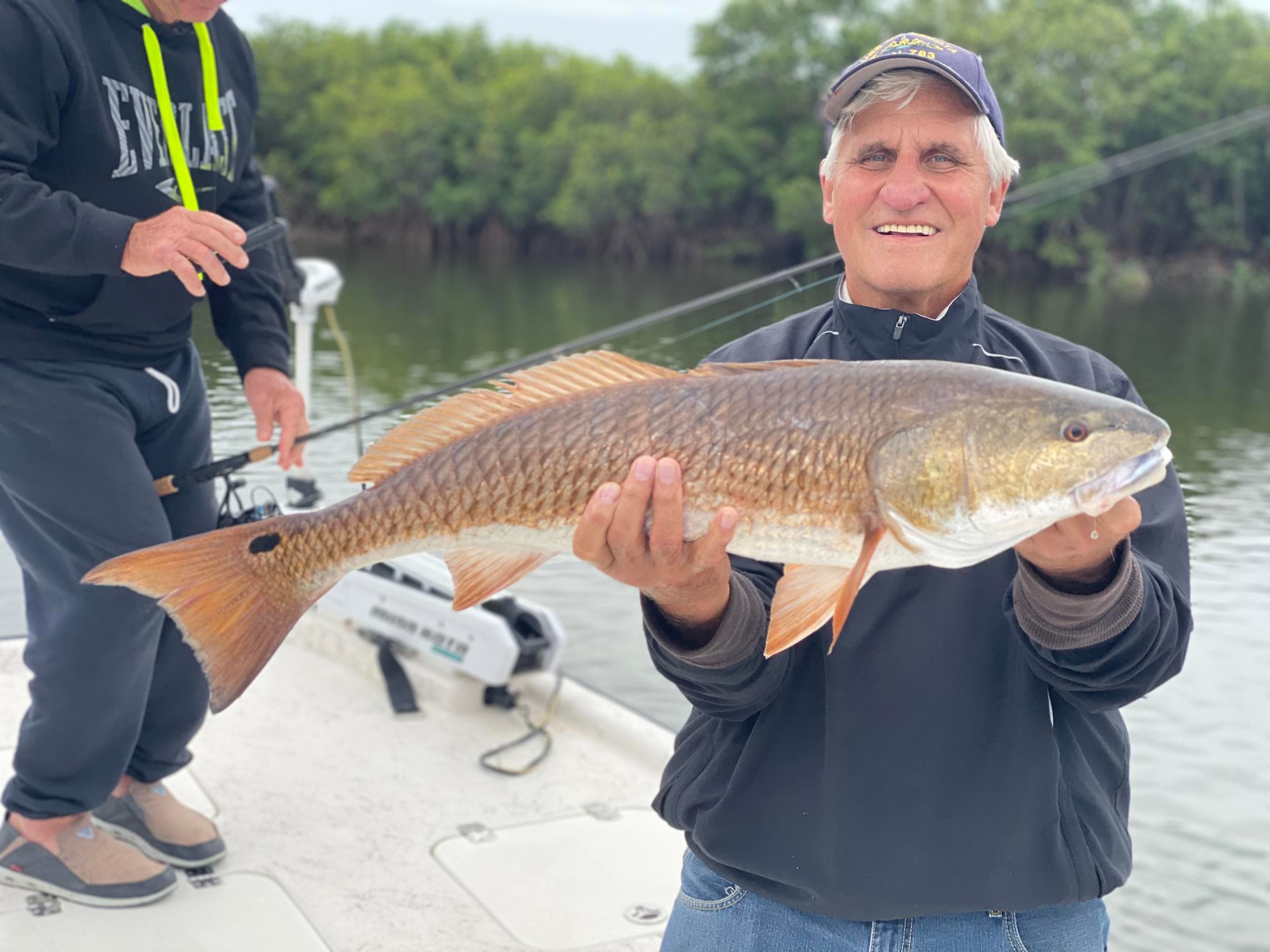 Angler holding large redfish aboard Florida flats fishing charter