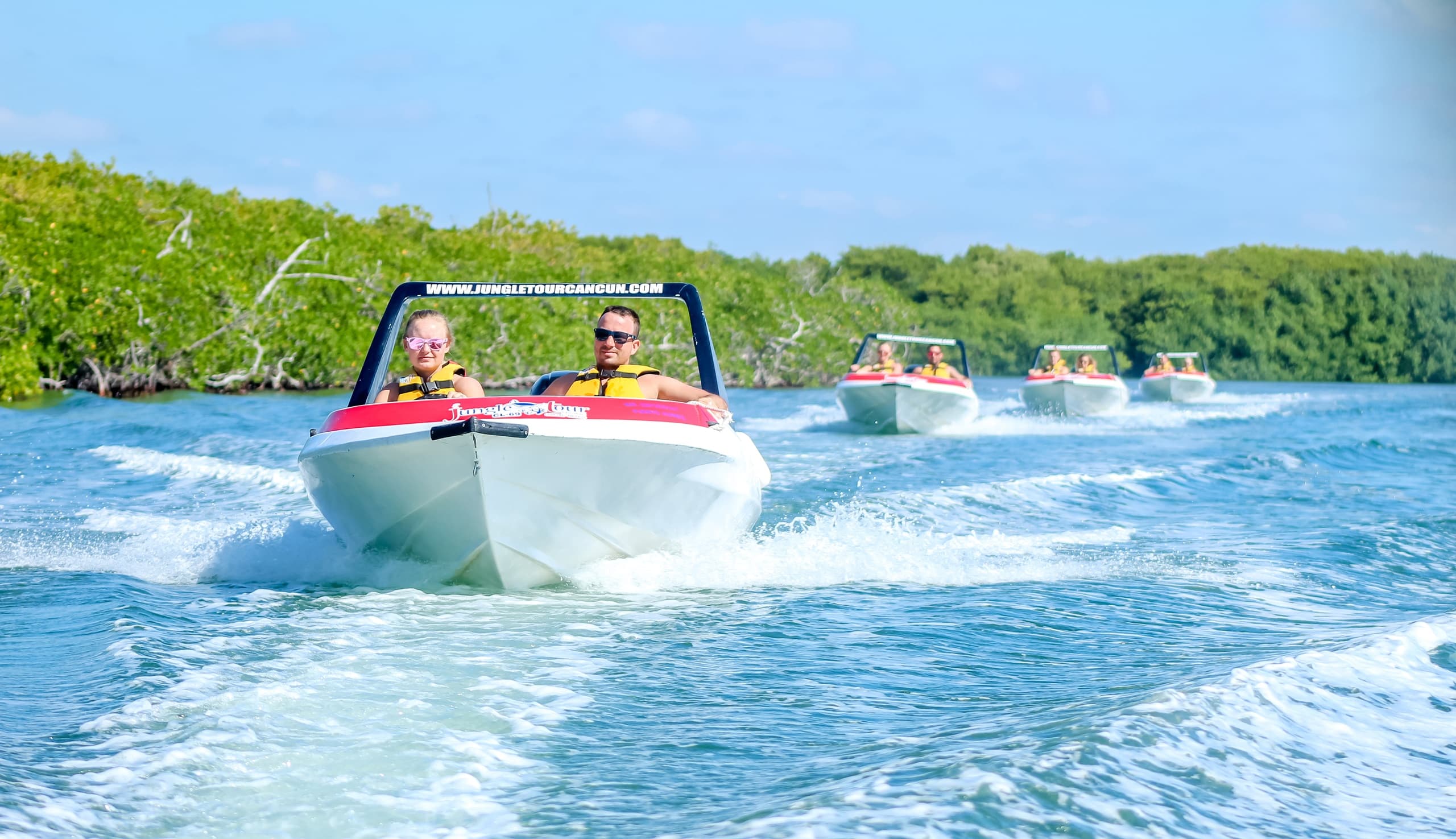Speedboats racing on turquoise mangrove-lined coastal waters