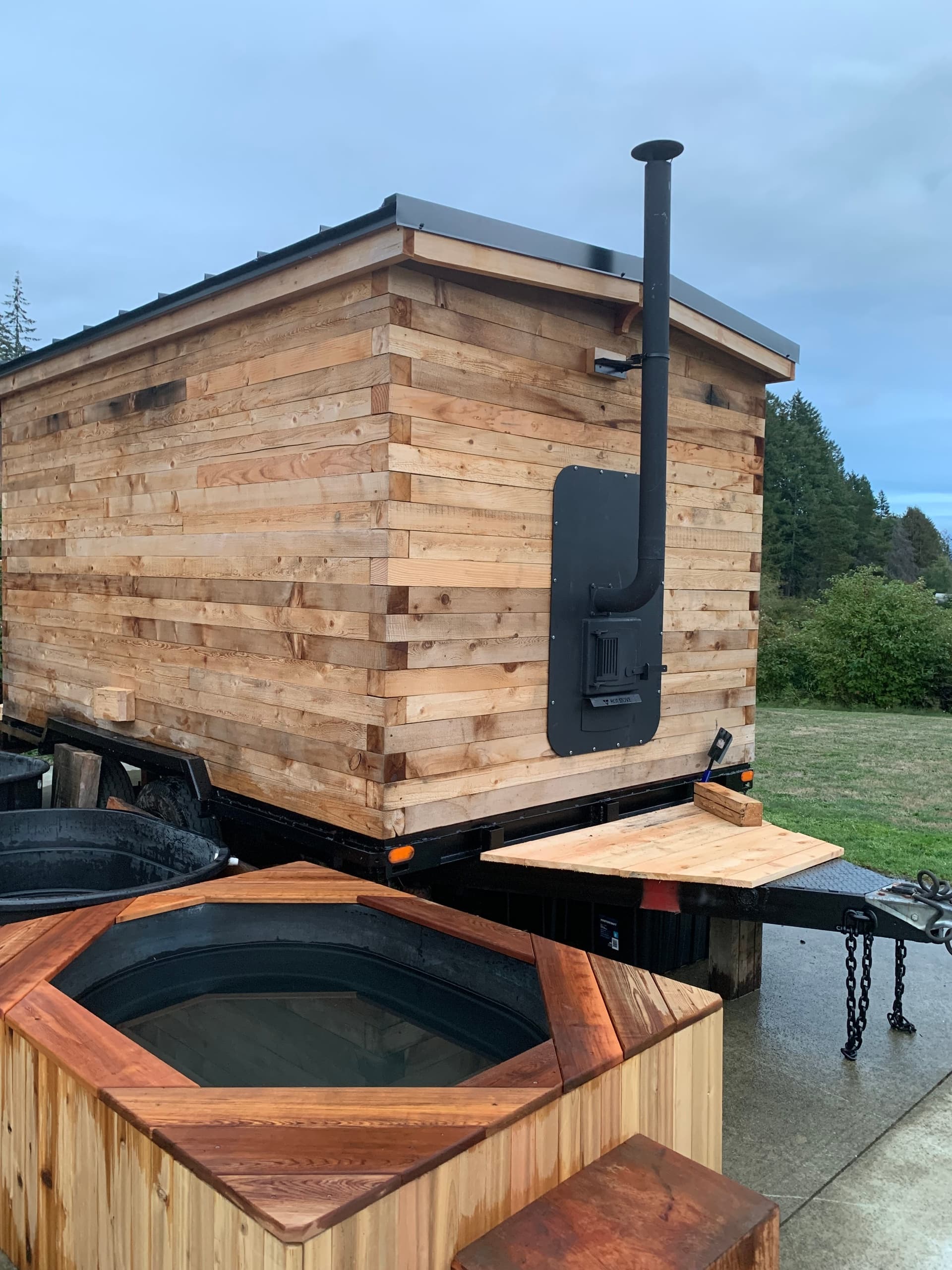 Mobile wood-fired sauna with cedar hot tub on trailer