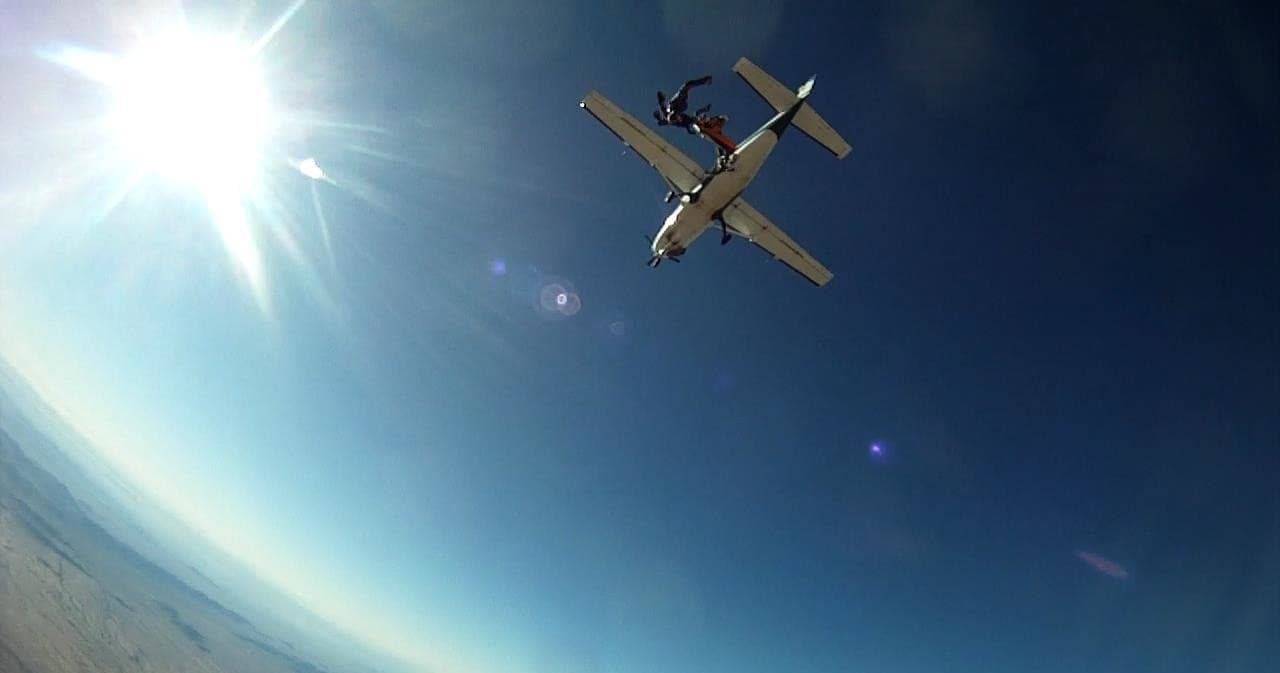 Skydiver exiting plane into clear blue sky over Arizona