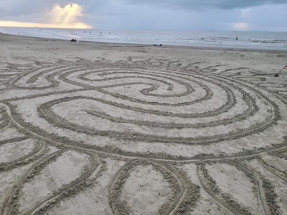 Spiral sand labyrinth on seaside beach at sunrise, beach art