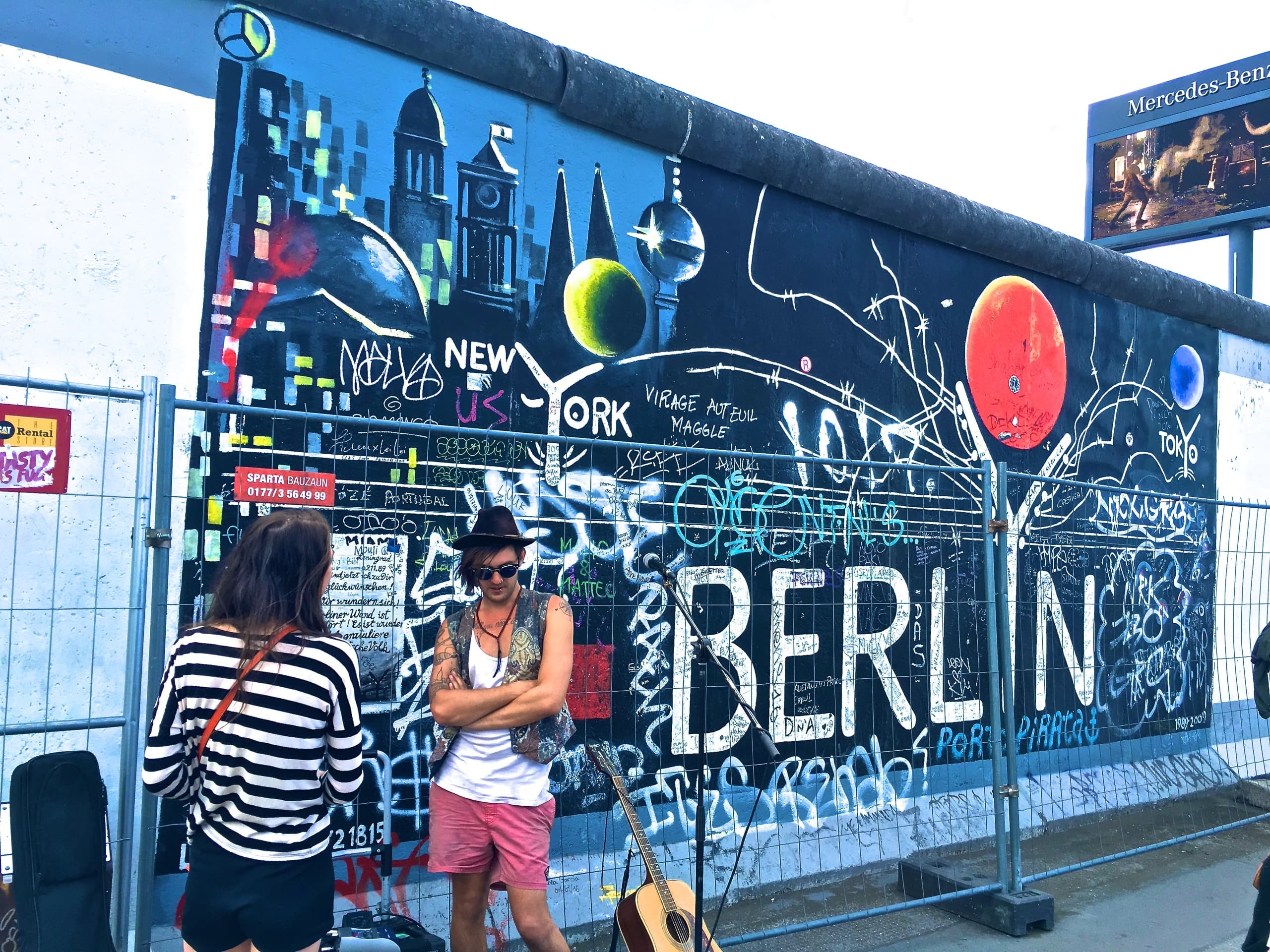 Street artists and tourists at East Side Gallery mural in Berlin